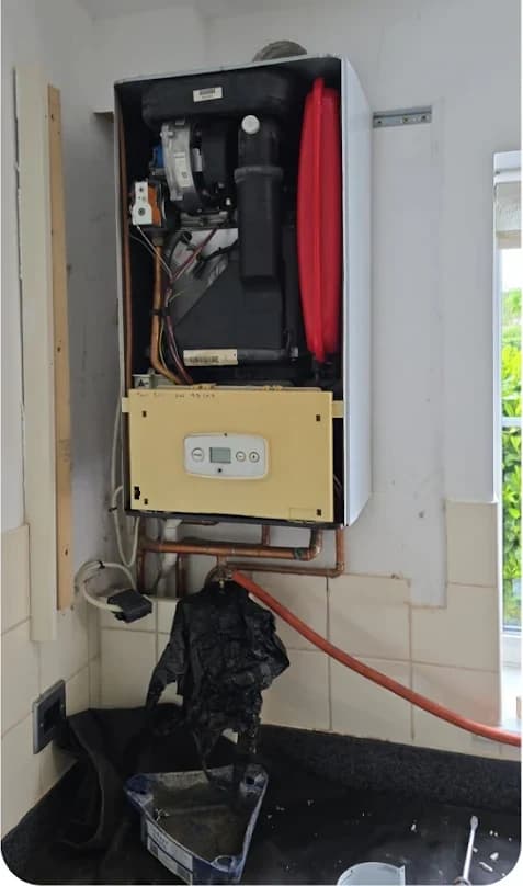 Old boiler removed showing exposed wiring and pipework
