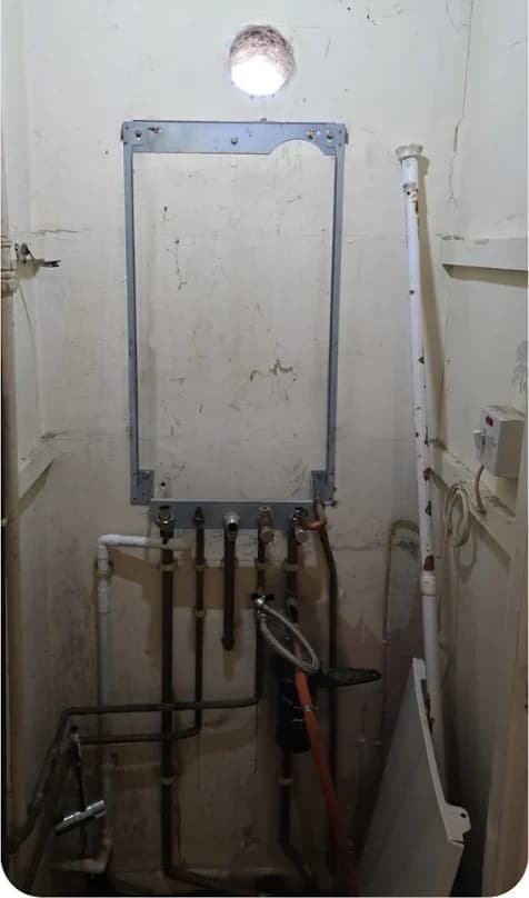 Old boiler frame and exposed copper pipes before replacement