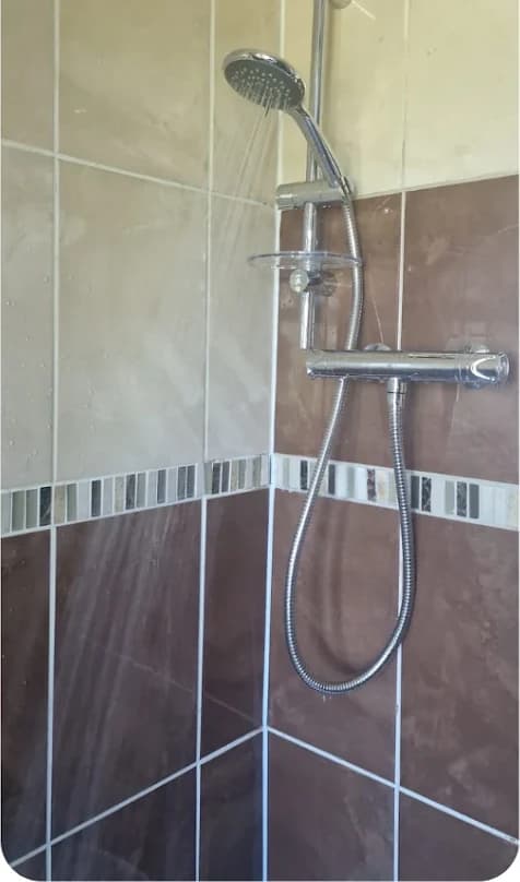 Newly installed thermostatic shower with dark tiling