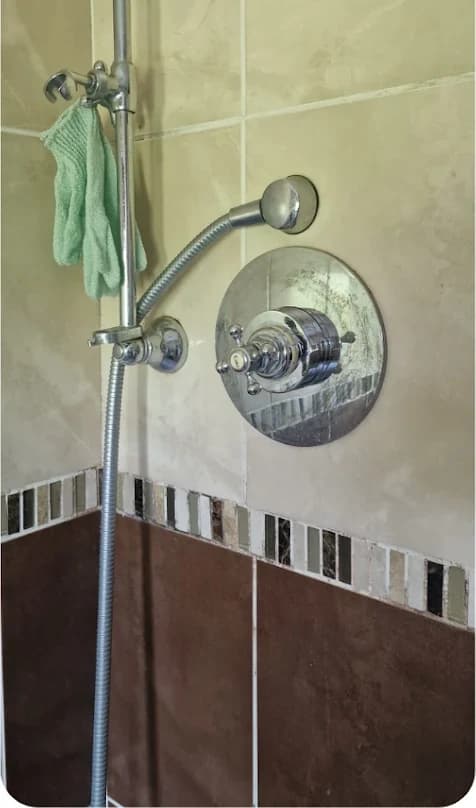Dated shower fitting and old tiling before replacement